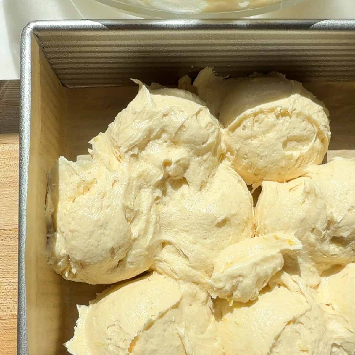 Lemon brownie batter scoops in prepared baking pan.