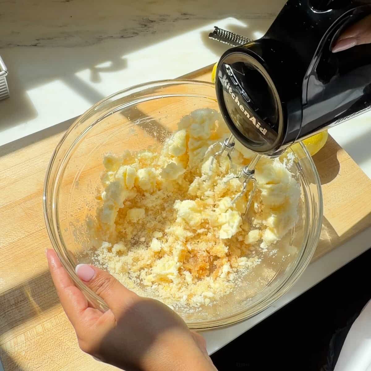 Beating softened butter and sugar in a bowl with a hand mixer.