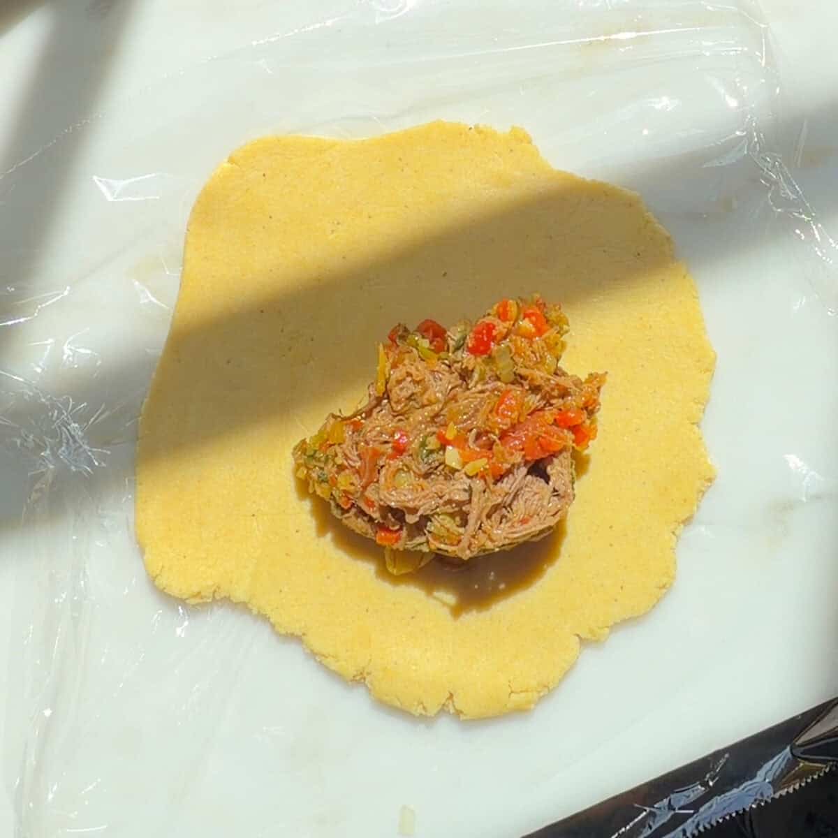 Filling in the center of empanada dough disc.
