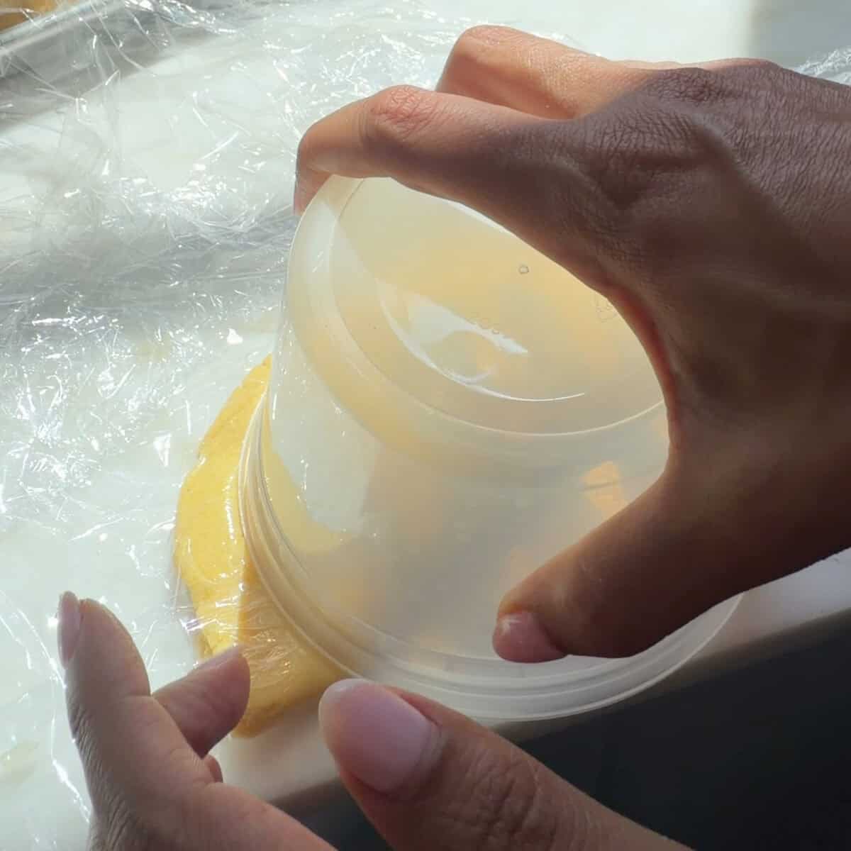 Sealing the empanada with a deli container.