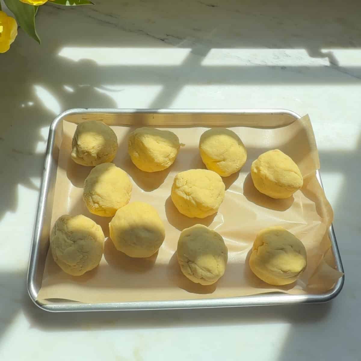 Empanada dough balls on baking sheet.
