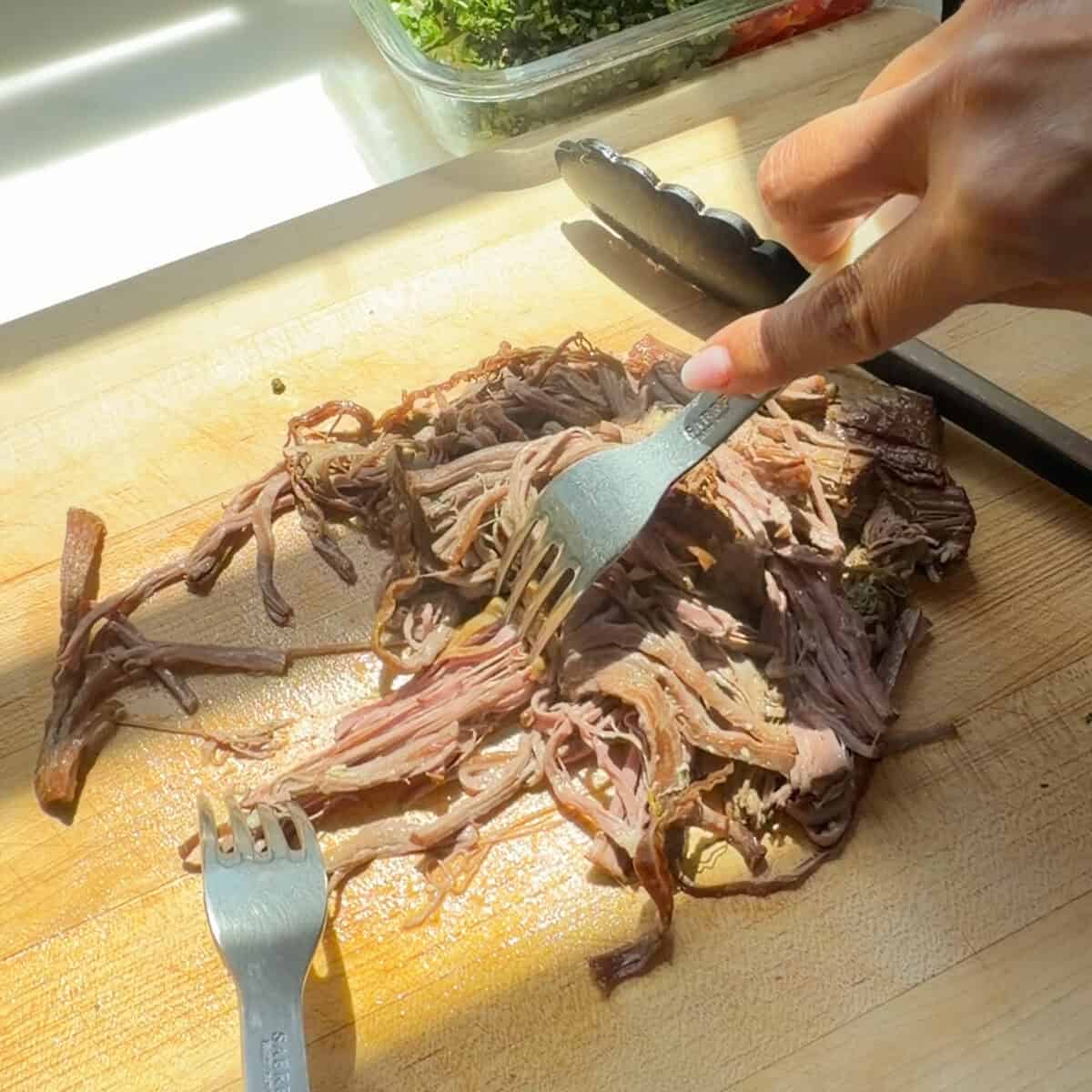 Shredding braised beef with forks.