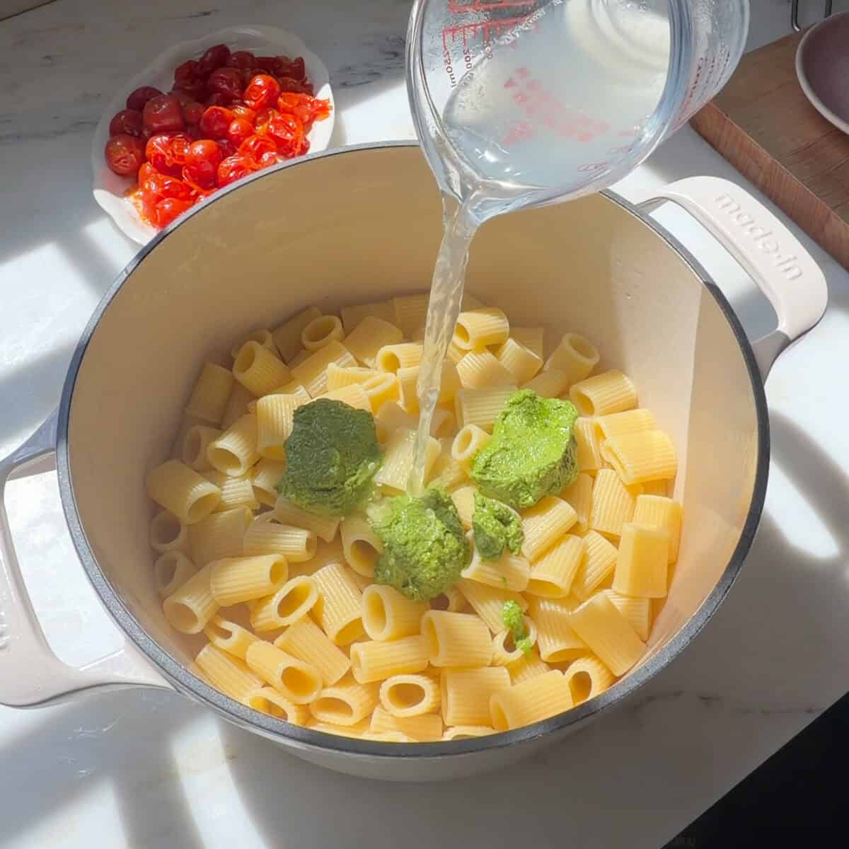 Pasta with dollops of pesto and pasta water poured over.