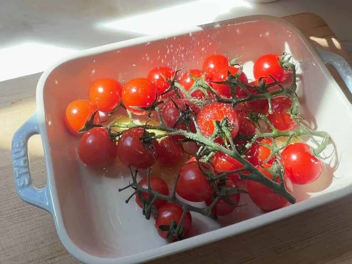 Cherry tomatoes with salt and olive oil in baking dish.
