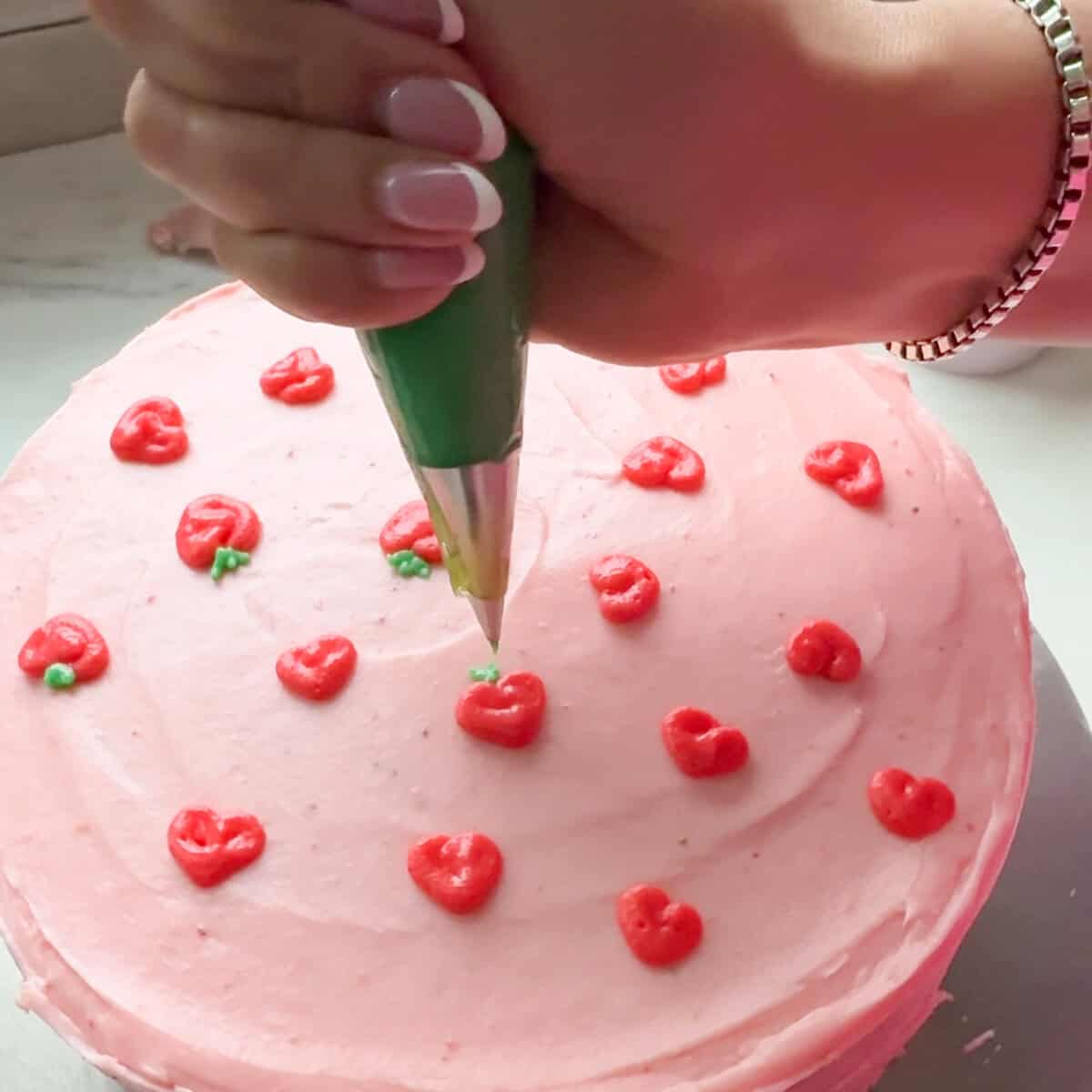 Decorating Strawberry Layer Cake with strawberries made of frosting.