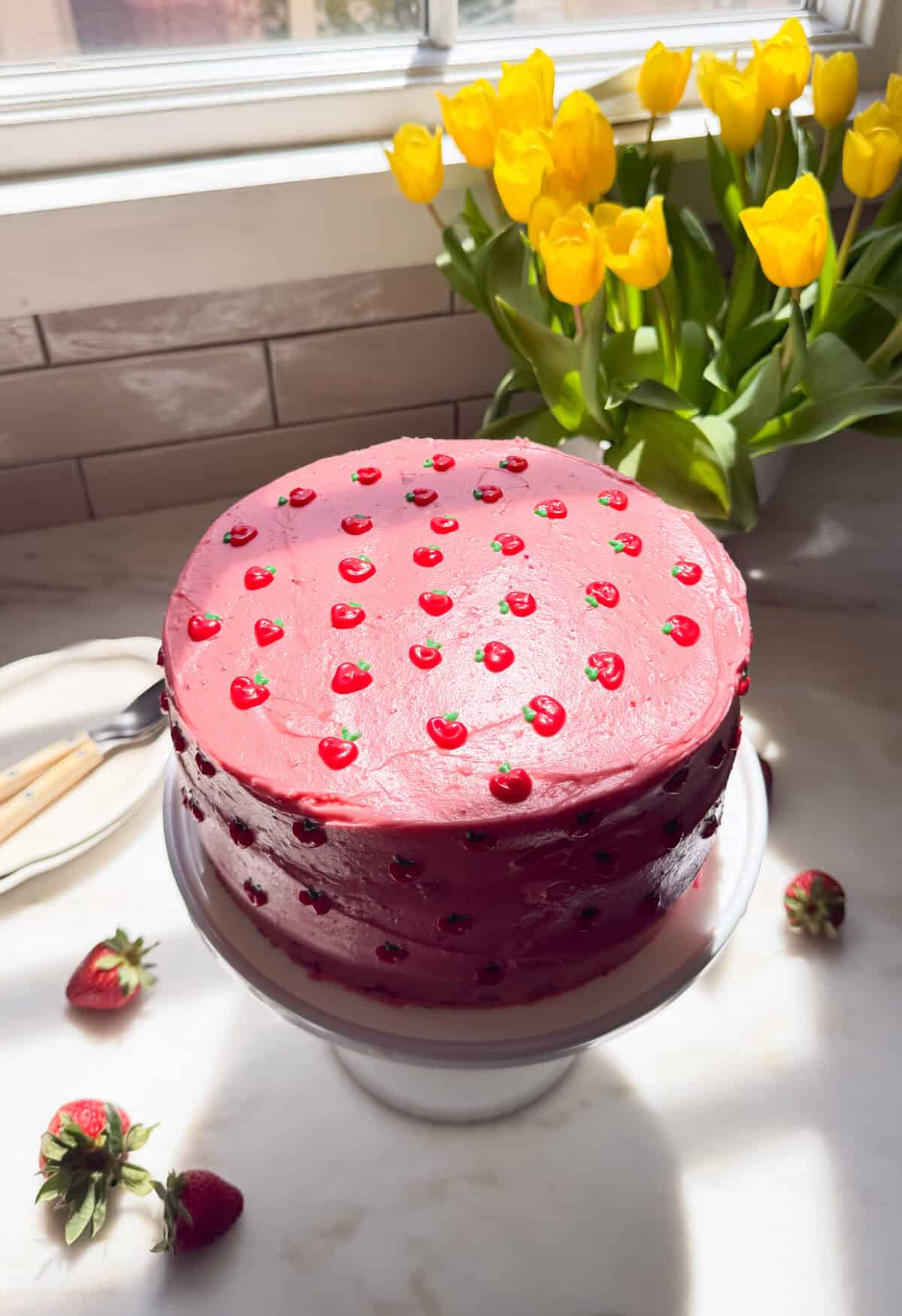 Decorated strawberry layer cake on cake stand.