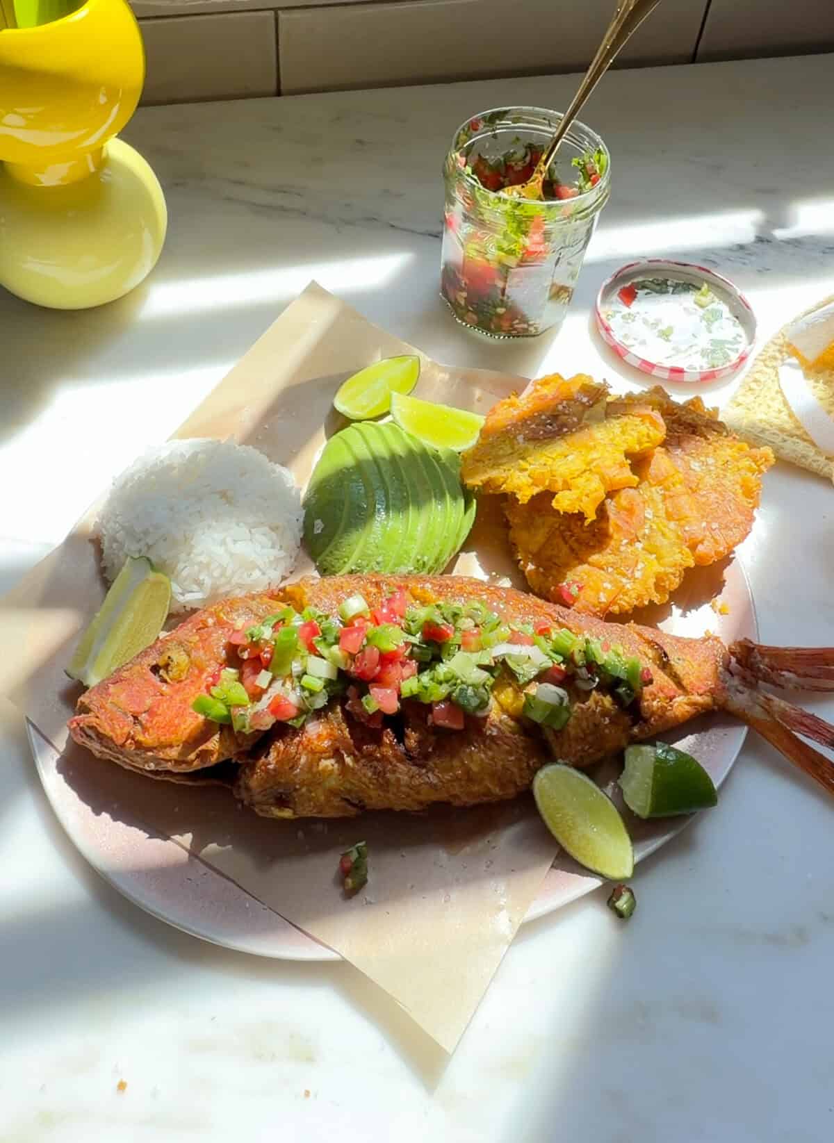 Pescado Frito with aji picante, tostones, avocado, and white rice on a plate.