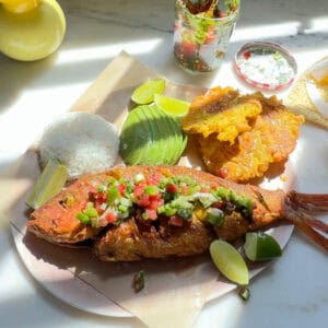 Pescado Frito with aji picante, tostones, avocado, and white rice on a plate.