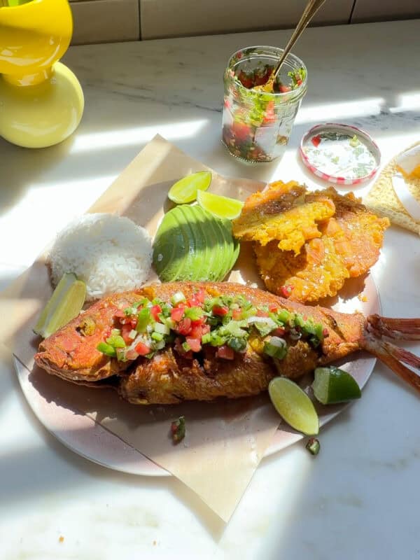 Pescado Frito with aji picante, tostones, avocado, and white rice on a plate.