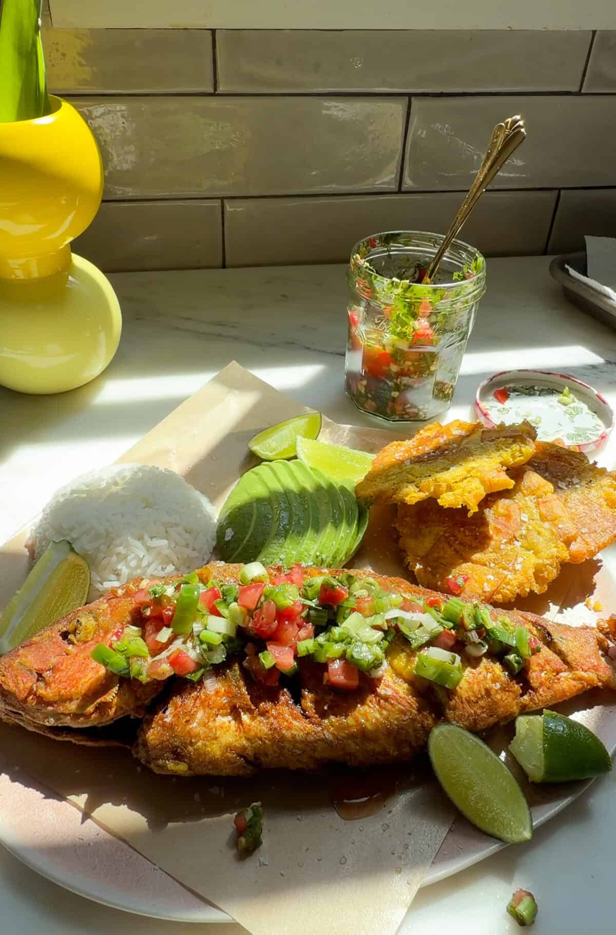 Pescado Frito with aji picante, tostones, avocado, and white rice on a plate.