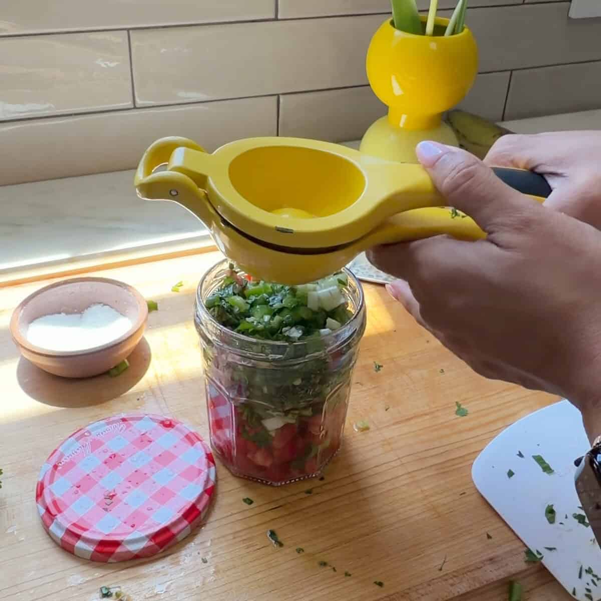 Squeezing lime juice into jar of aji picante.
