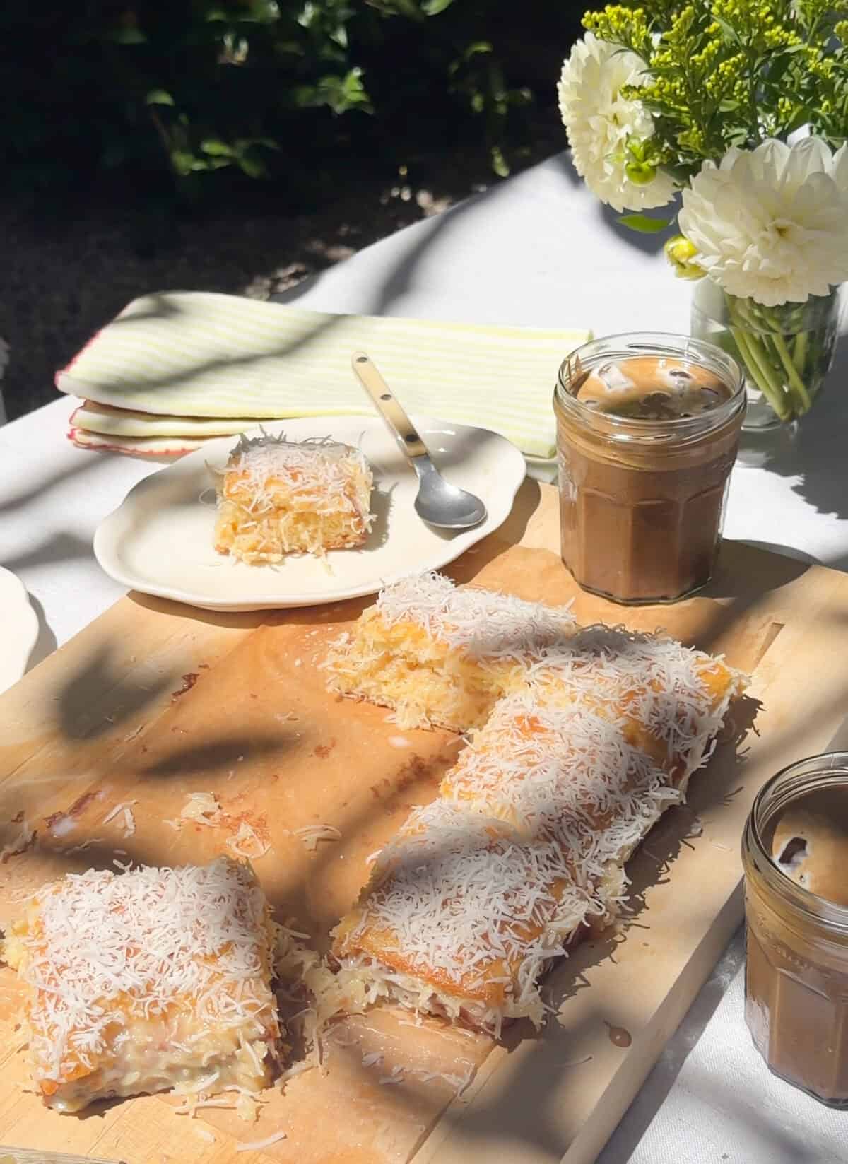 Cake slices on cutting board and plates with glasses of iced coffee.