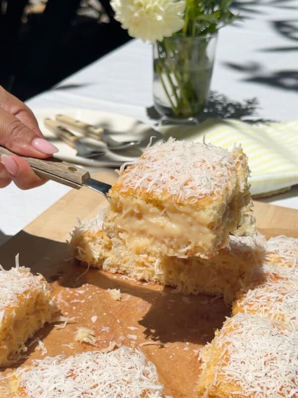 Slice of cake on spatula with slices of cake on a cutting board.
