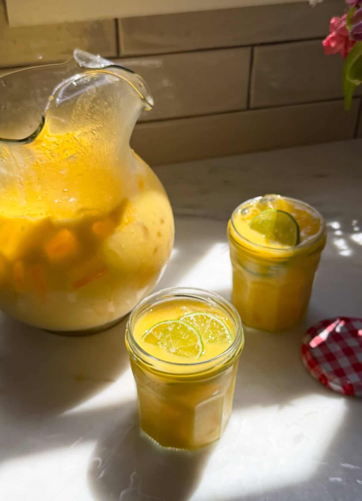 Glasses and pitcher of creamy mango agua fresca.