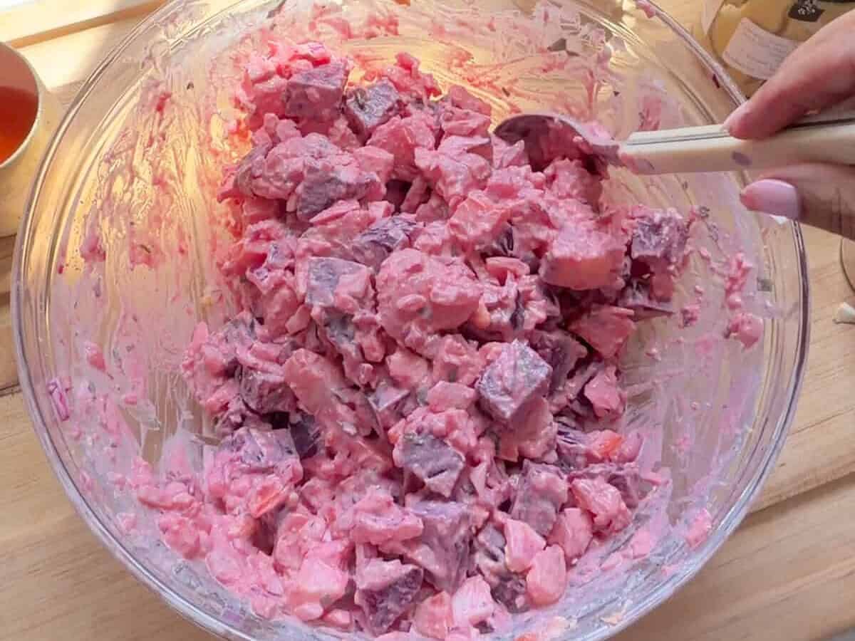Mixing Haitian potato salad together in a bowl.
