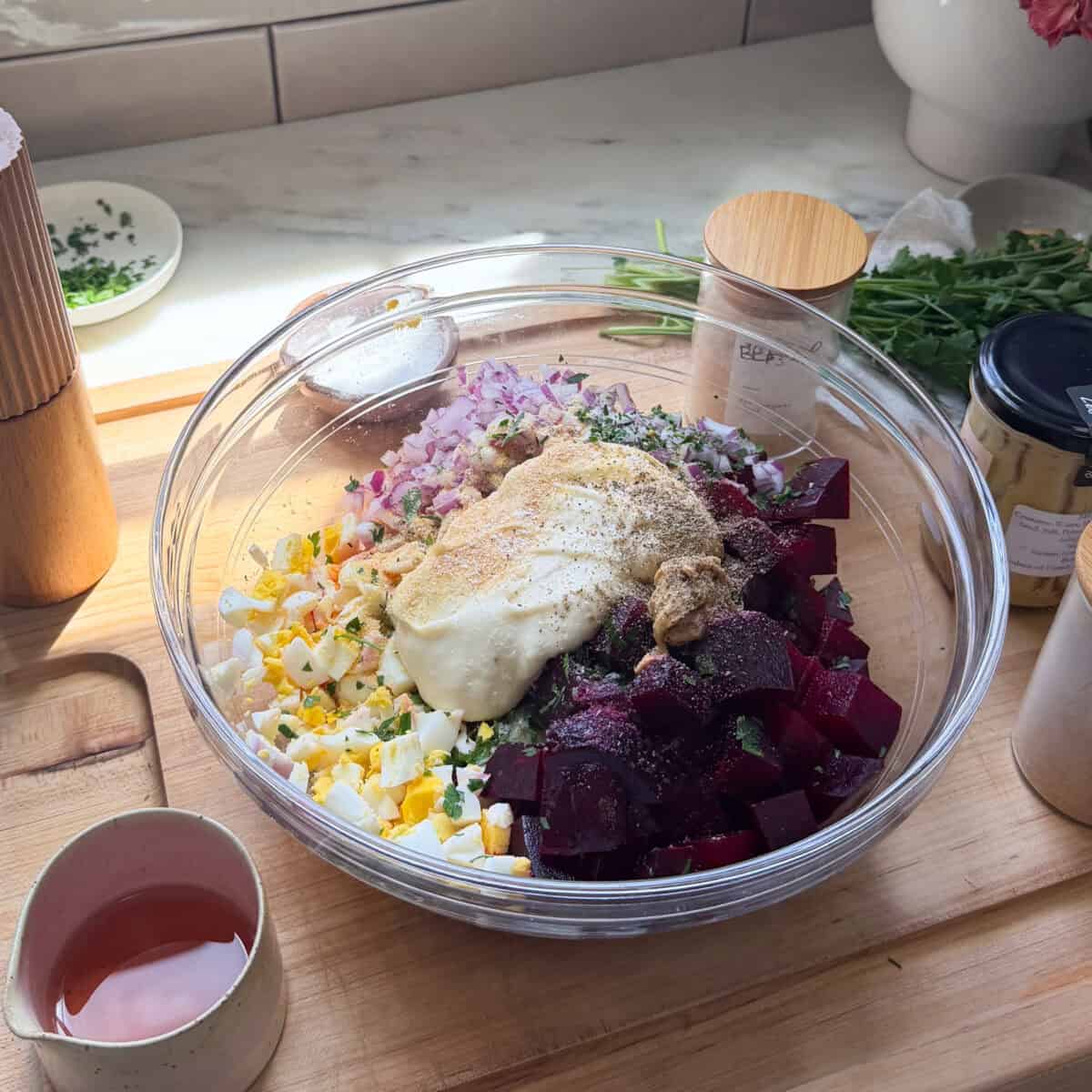 Diced beets, boiled eggs, and red onion with mayo and spices in a bowl.