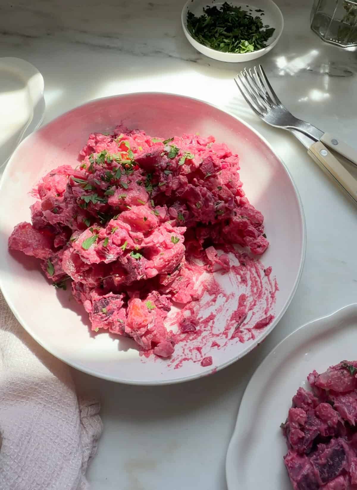 Haitian potato salad with a parsley garnish in a bowl.