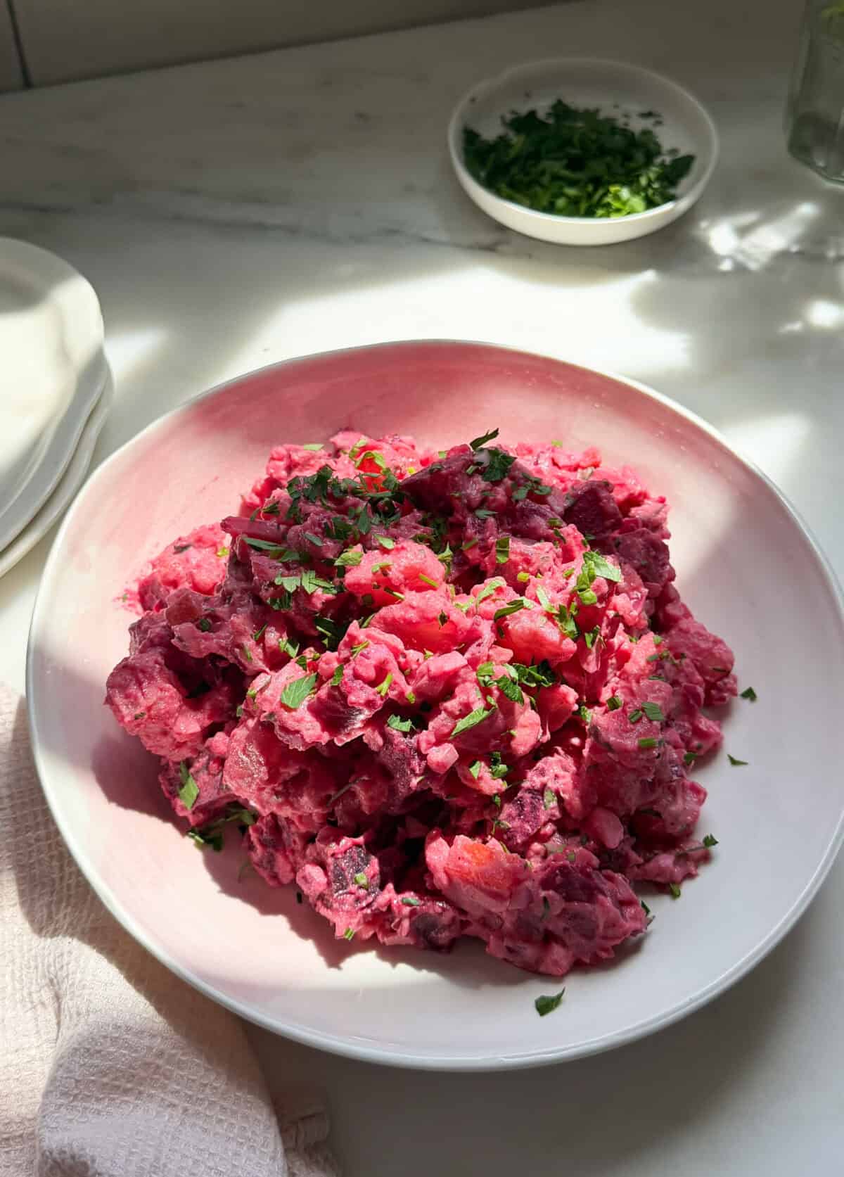 Haitian potato salad with a parsley garnish in a bowl.