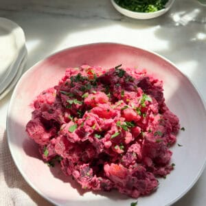 Haitian potato salad with a parsley garnish in a bowl.