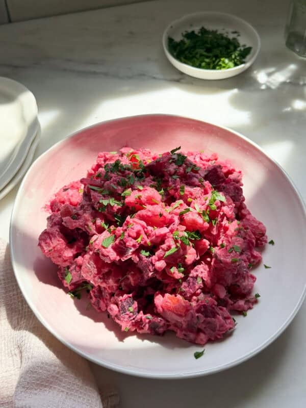 Haitian potato salad with a parsley garnish in a bowl.