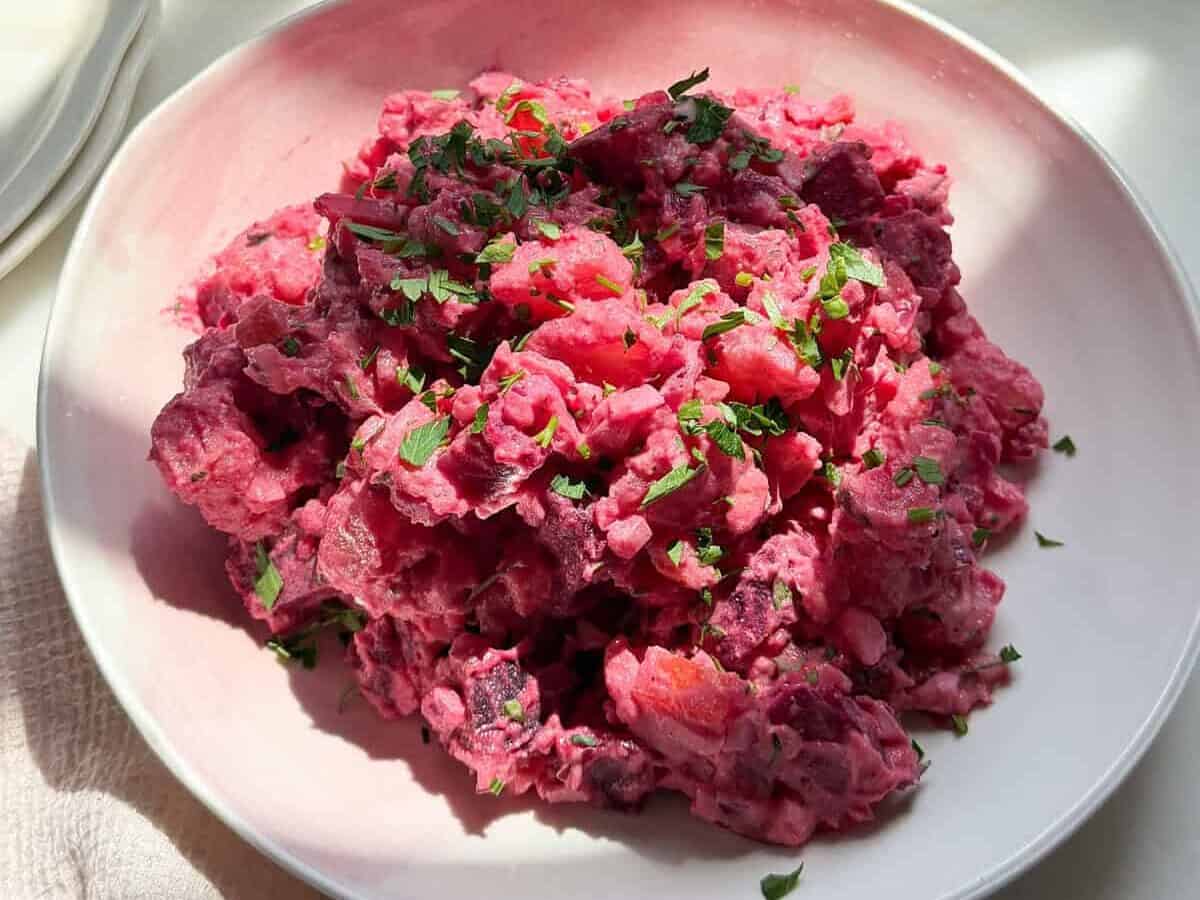 Haitian potato salad with a parsley garnish in a bowl.