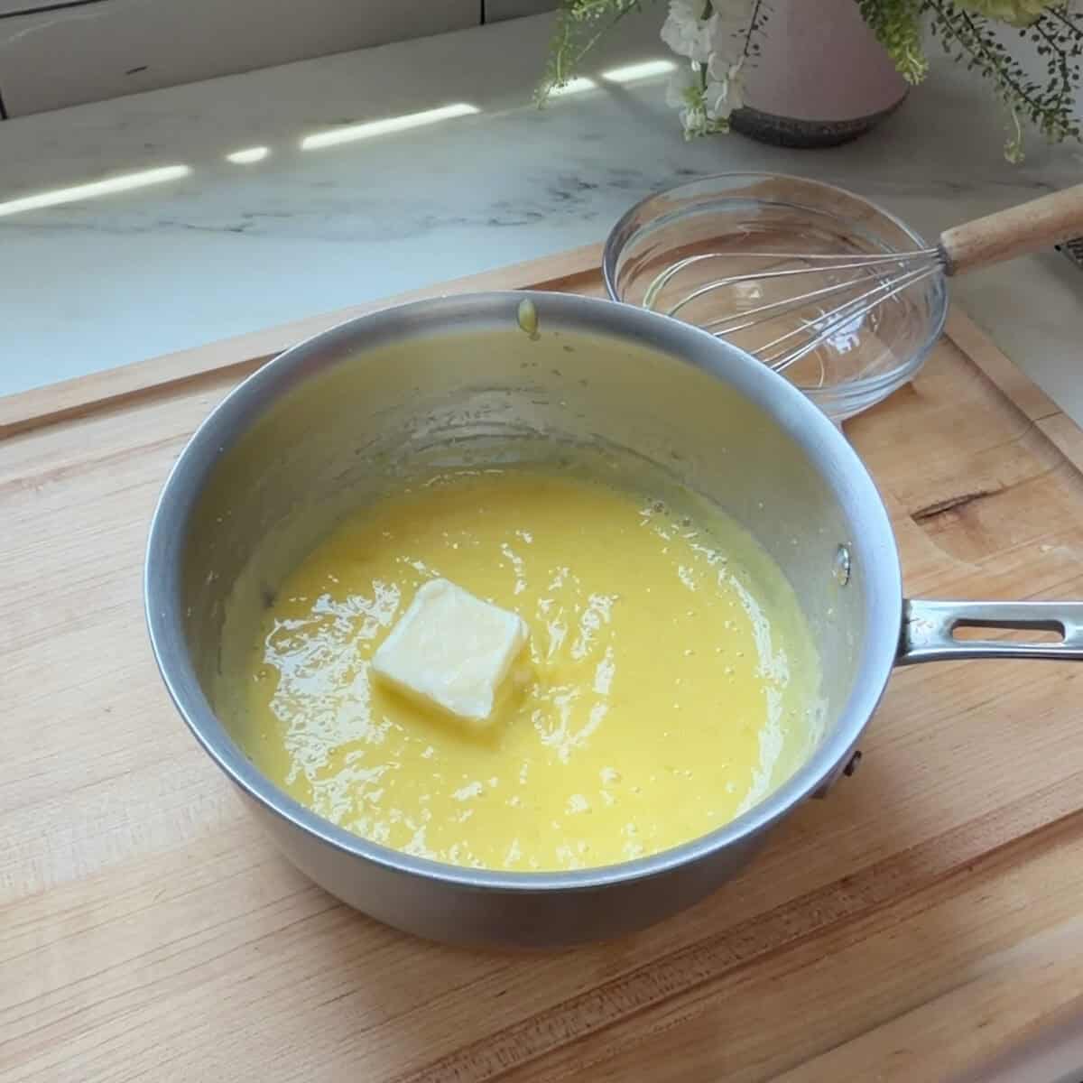Room temperature butter added to the key lime curd in a medium saucepan.