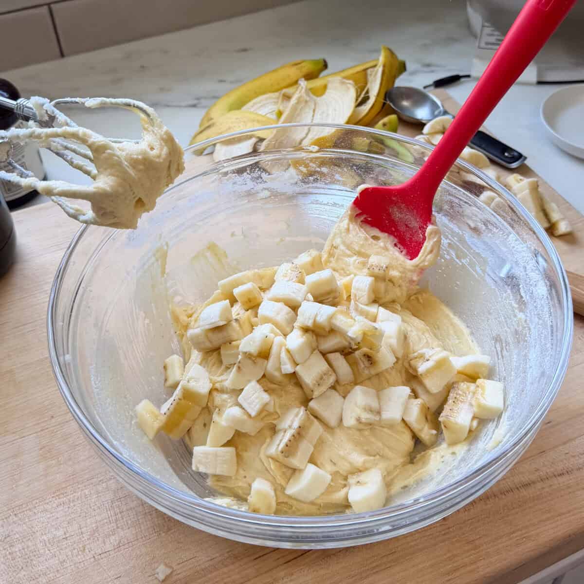 Diced bananas on top of Banana Pudding Brownie batter in bowl.