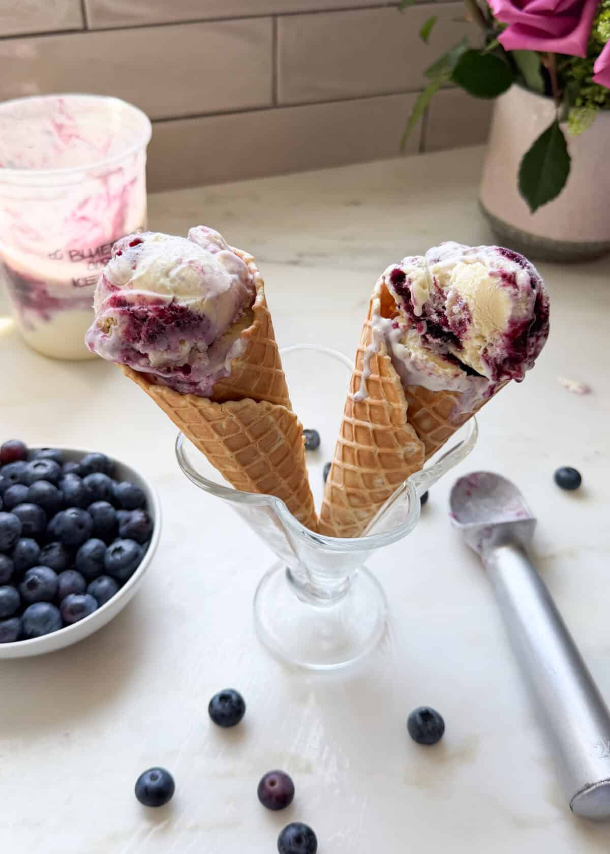 Melty ice cream cones in a sundae cup with blueberries in a bowl.