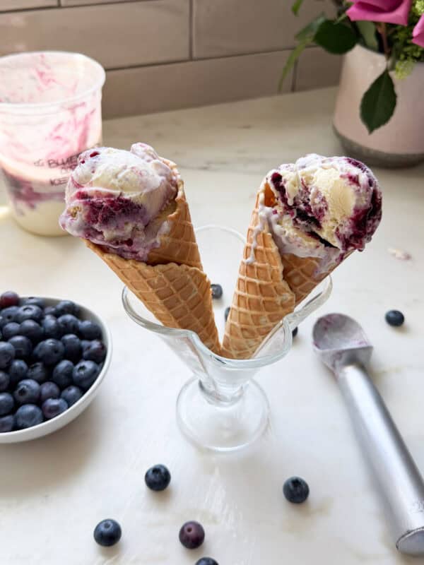 Melty ice cream cones in a sundae cup with blueberries in a bowl.