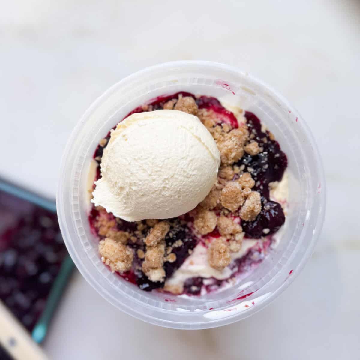 Layers of blueberry compote, crumble, and ice cream in a quart deli container.