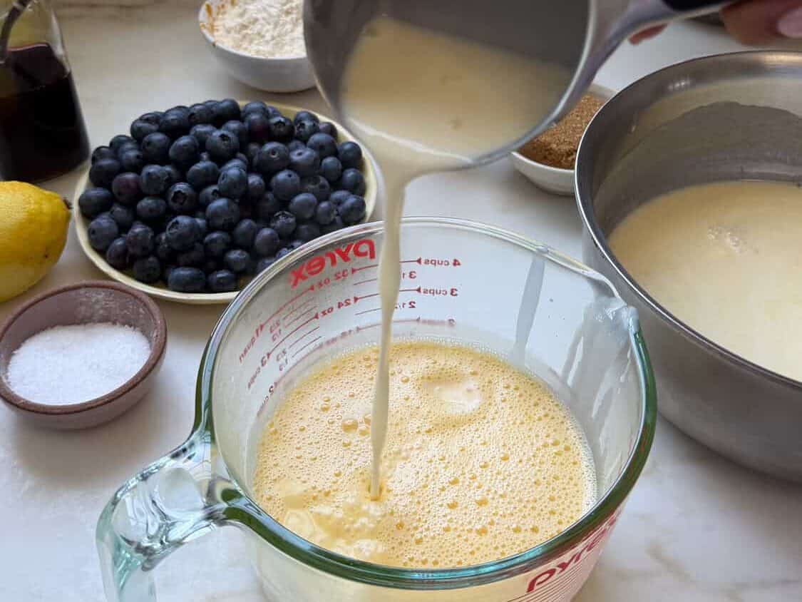 Pouring hot cream mixture into egg yolk base.