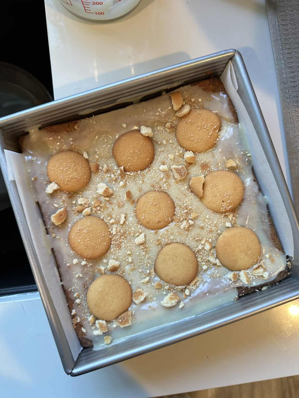 Glazed banana pudding brownies with Nilla wafers on top in baking pan.
