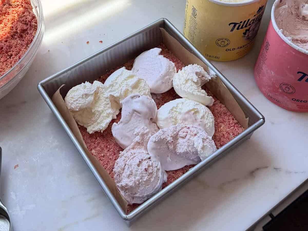 Scoops of strawberry and vanilla ice cream on top of the crushed Golden Oreos layer.