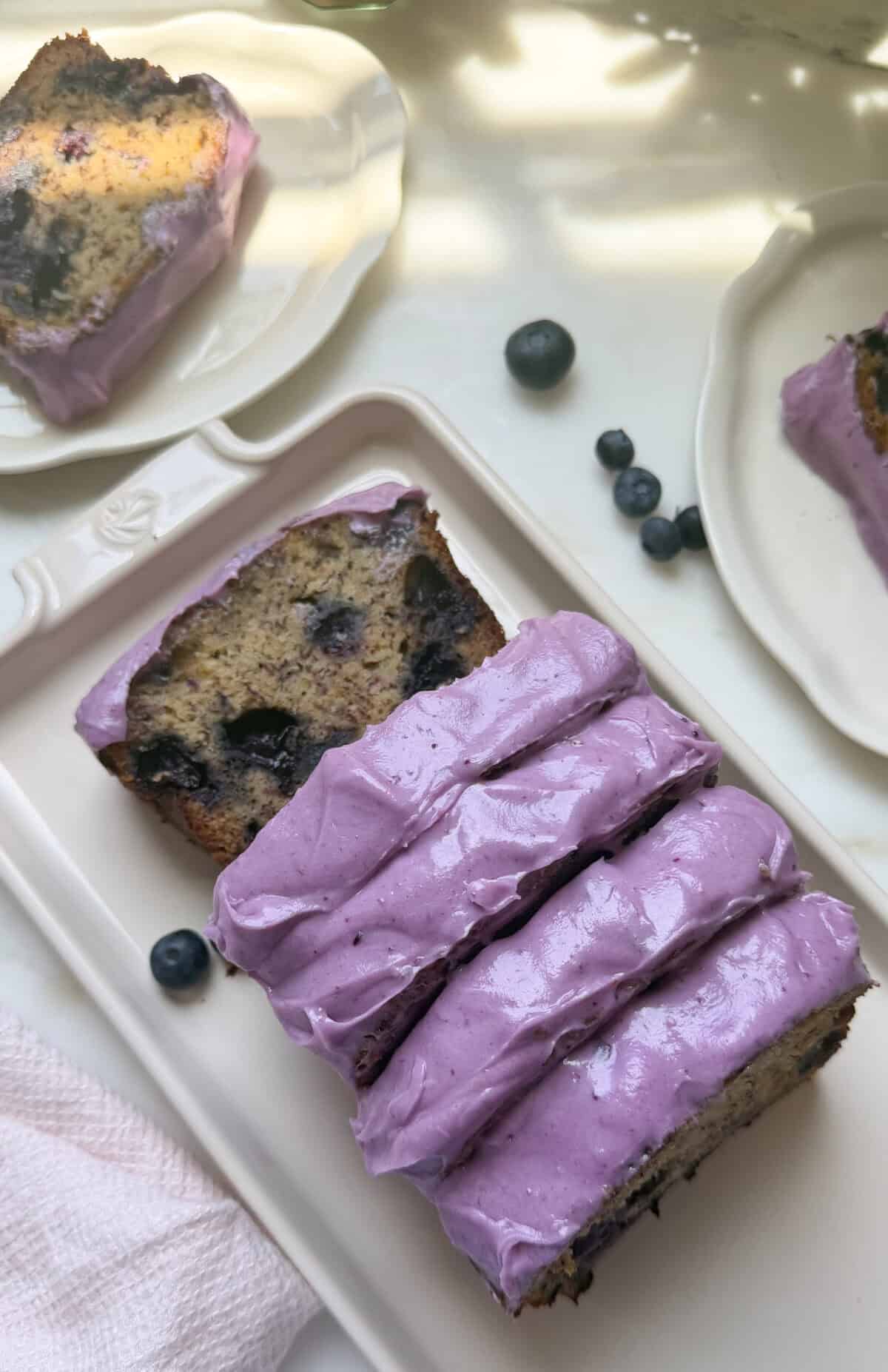 Sliced blueberry banana bread loaf on a platter.