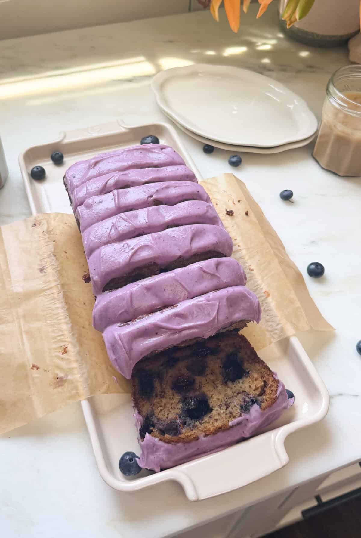 Sliced blueberry banana bread loaf on a platter.
