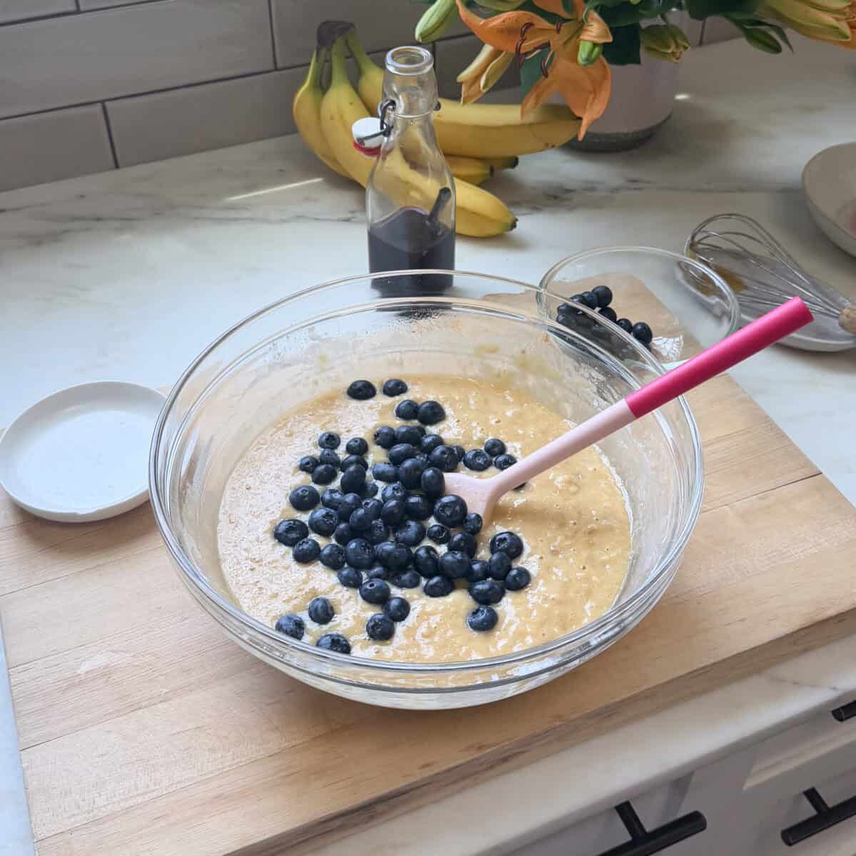 Blueberries on top of the banana bread batter in large bowl.