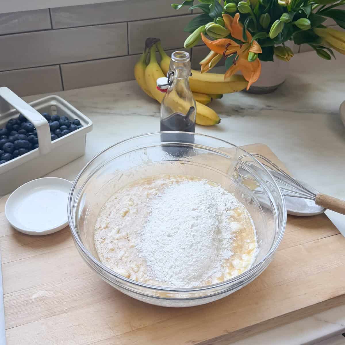Bowl of banana mixture with dry ingredients on top.