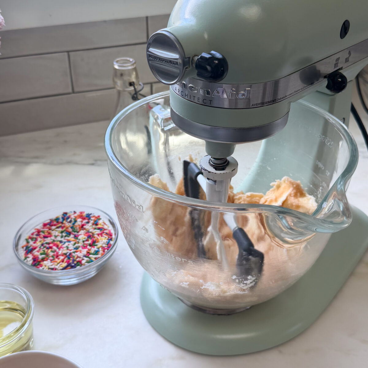 Butter, sugar, and vanilla extract in bowl of stand mixer with paddle attachment.
