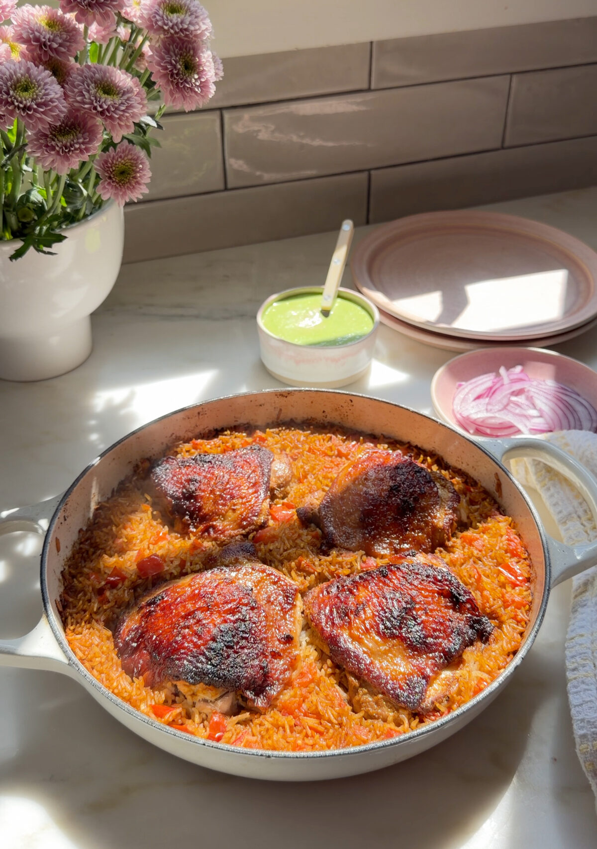 Cooked chicken and rice in braiser on counter with bowl of aji verde.