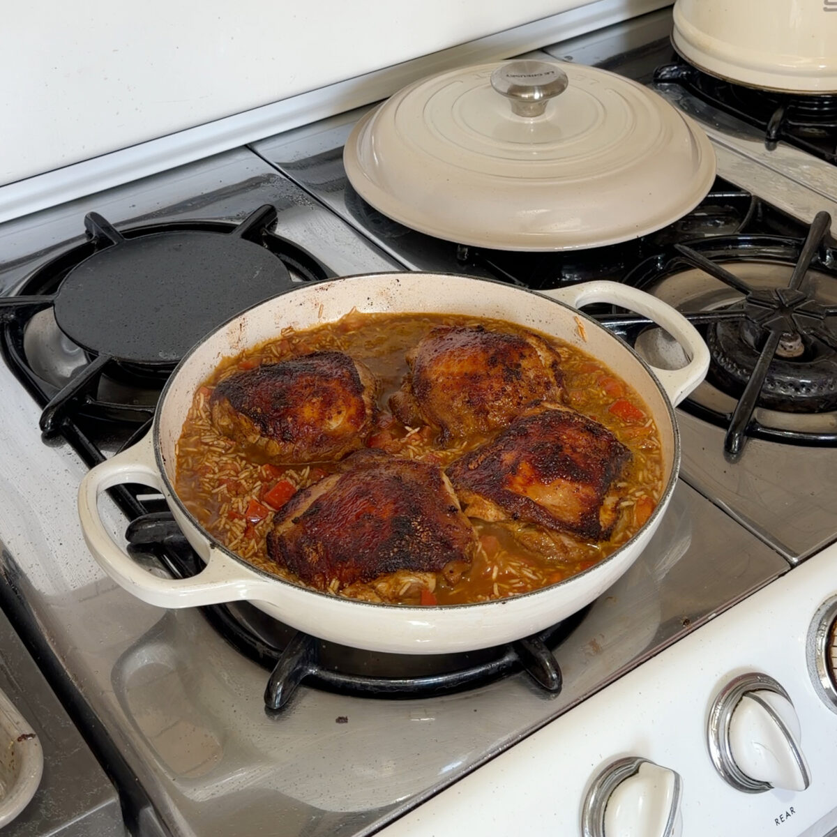Chicken and rice in braiser on stovetop.