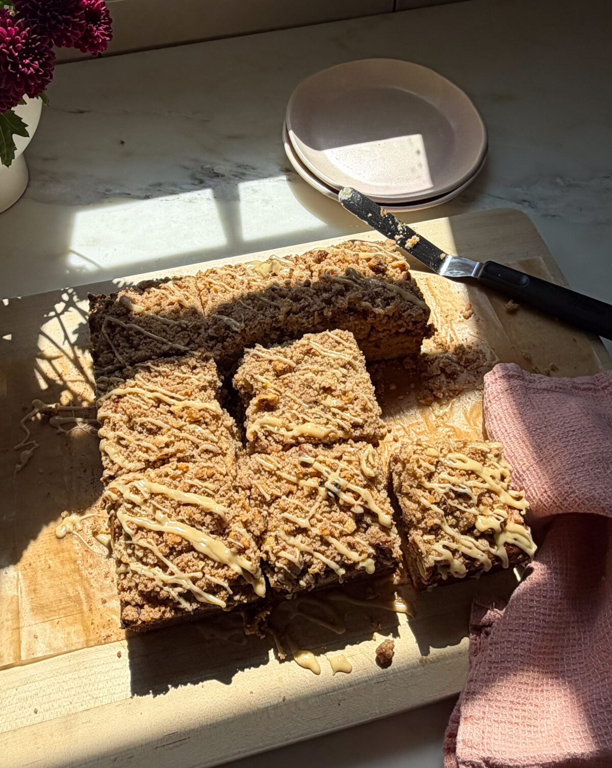 Glazed and sliced banana bread coffee cake on cutting board.