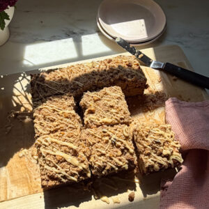 Glazed and sliced banana bread coffee cake on cutting board.