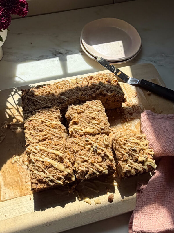 Glazed and sliced banana bread coffee cake on cutting board.