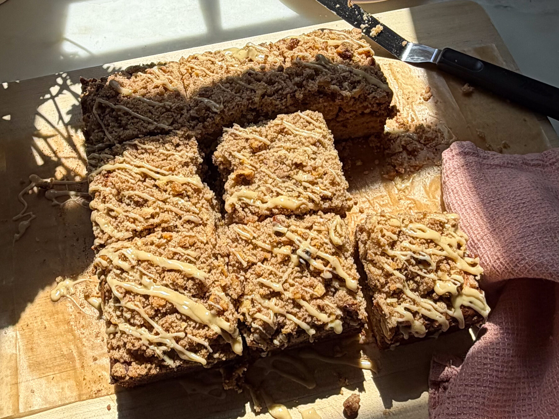 Glazed and sliced banana bread coffee cake on cutting board.