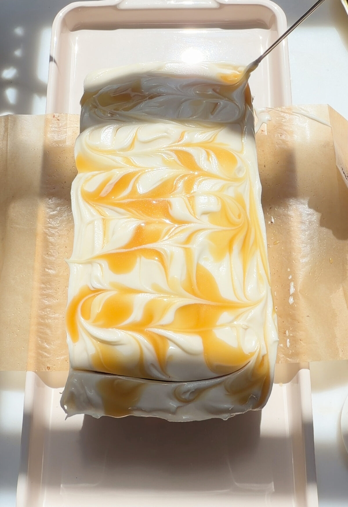 Swirling dollops of salted maple caramel into frosting on top of loaf.