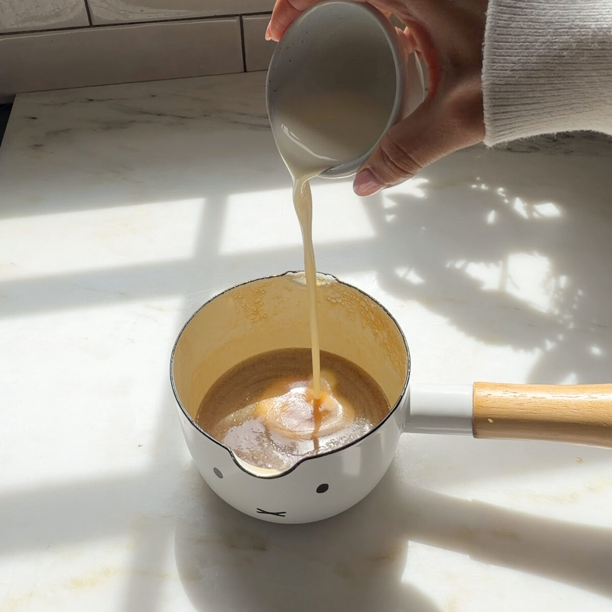 Pouring heavy cream into warm salted maple caramel.