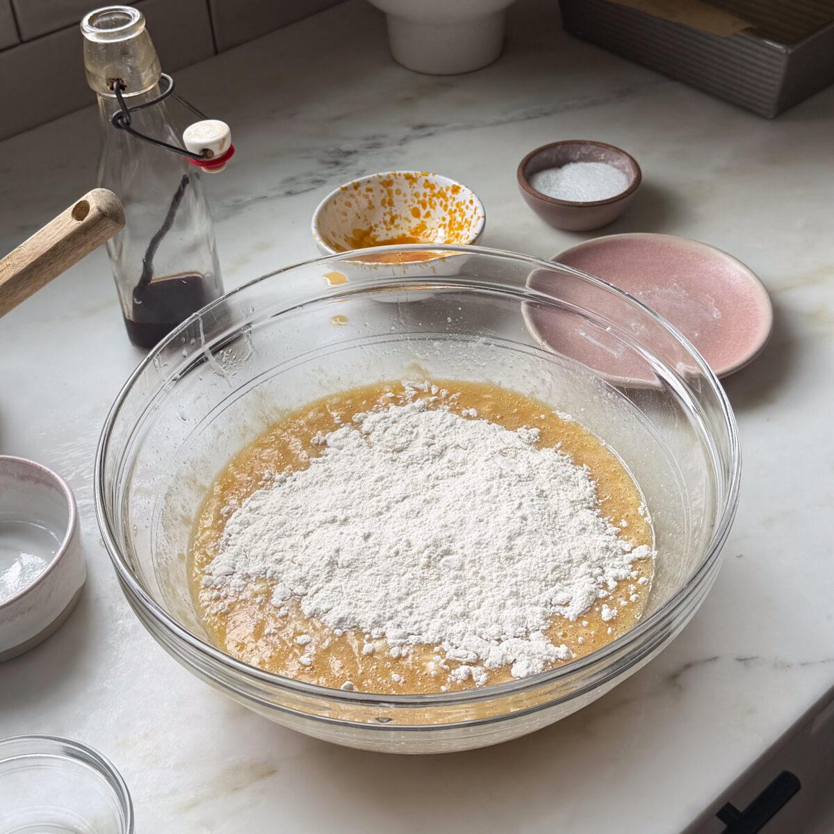 Dry ingredients atop wet ingredients for the salted maple banana bread in a large bowl.