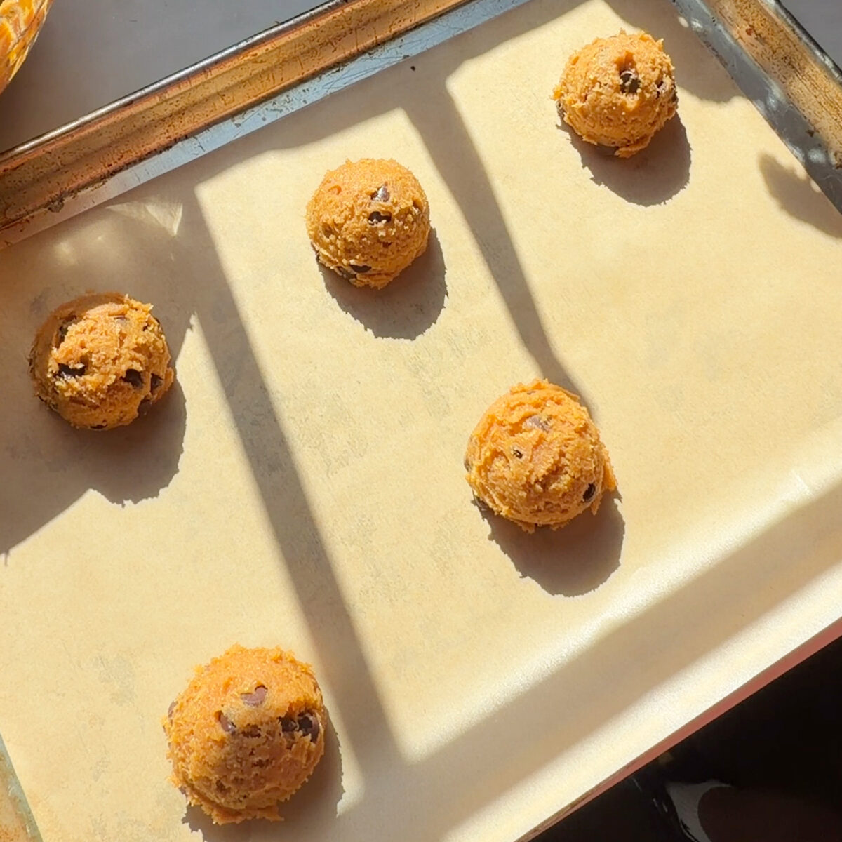 Cookie dough scoops on lined baking sheet.