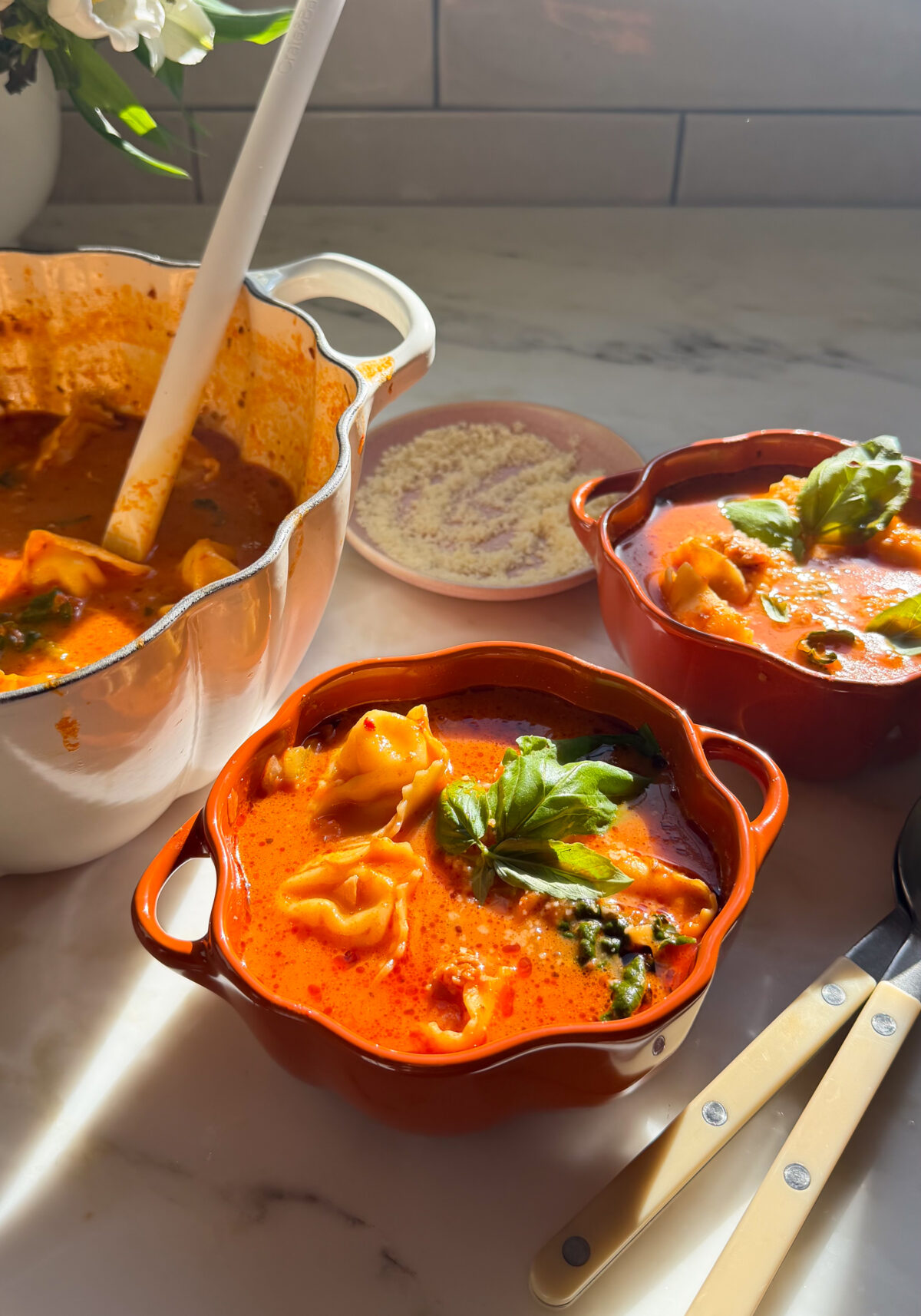 Bowls of tortellini soup with a fresh basil garnish.