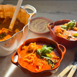 Bowls of tortellini soup with a fresh basil garnish.
